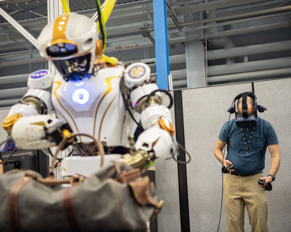 NASA's Valkyrie humanoid robot lifting a bag during a demonstration controlled by Shaun Azimi